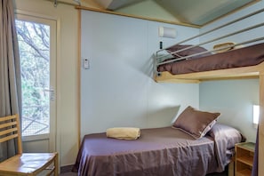 Een kleine kamer met een stapelbed, een enkel bed, een tafeltje en een stoel.