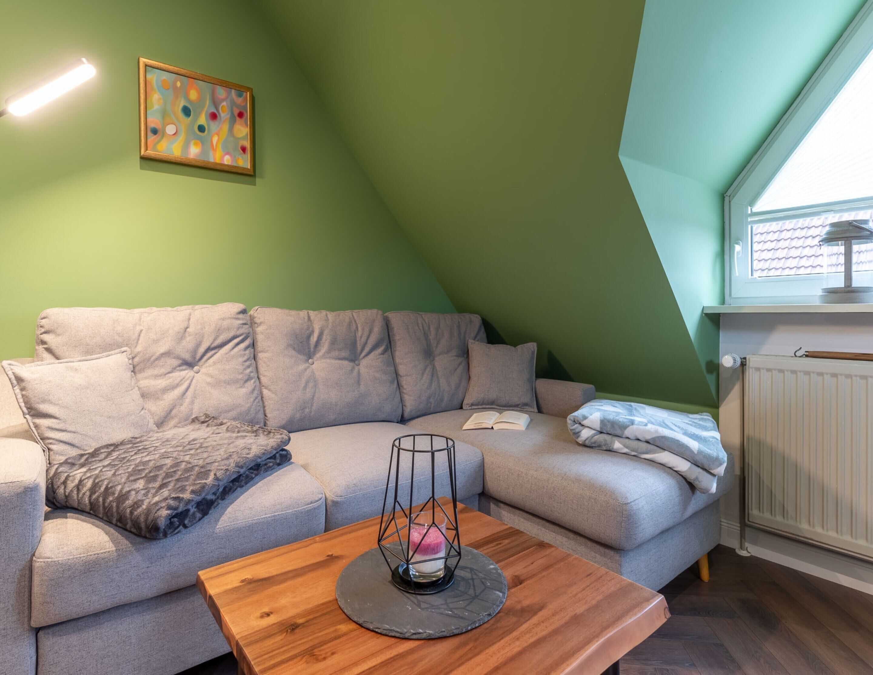 Un salon chaleureux avec un canapé gris, une table basse en bois et un tableau accroché au mur.