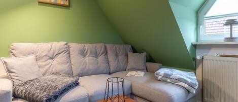 Un salon chaleureux avec un canapé gris, une table basse en bois et un tableau accroché au mur.
