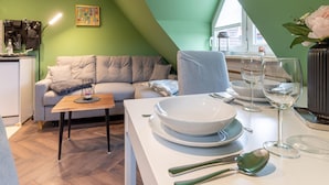 A dining area with a table set for two, a sofa, and a painting on the wall. - Charmante Ferienwohnung (Büsum)