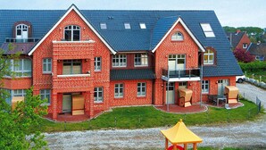 Un edificio de ladrillo rojo con un balcón y un parque infantil con toboganes y estructuras para escalar.