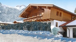 Een houten chalet met balkon, omringd door besneeuwde bergen.