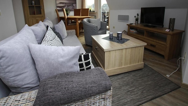 Un salon moderne comprenant un canapé, une table basse, un téléviseur et un meuble en bois.