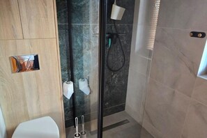 Un bagno moderno con cabina doccia in vetro, un water e un porta asciugamani.