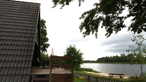 A wooden deck with a staircase leading to a building with a tiled roof, overlooking a lake. - Ferienhaus mit Terrasse, Haustierfrei (Clausthal-Zellerfeld)