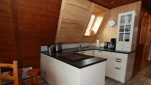 A compact kitchen with a central island, wooden cabinetry, a built-in oven, and a small window. - Ferienhaus mit Terrasse, Haustierfrei (Clausthal-Zellerfeld)