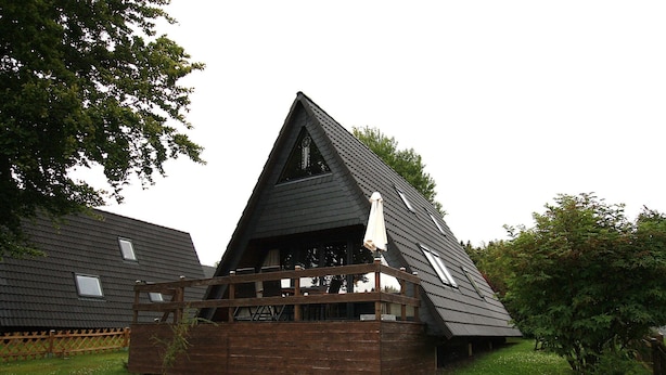 A triangular wooden structure with a balcony, surrounded by a wooden fence and greenery. - Ferienhaus mit Terrasse, Haustierfrei (Clausthal-Zellerfeld)