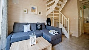Un salon chaleureux avec un canapé gris, une lanterne blanche et un escalier en bois.