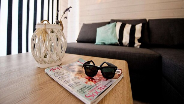 Un magazine, des lunettes de soleil et un vase décoratif sur une table en bois.