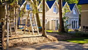 Un quartier résidentiel avec des maisons, une aire de jeux dotée d’une échelle en bois et un chemin piétonnier dallé.