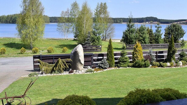Jardín ajardinado con un banco, una piedra y vistas a un lago.