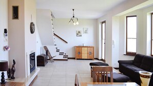 Un amplio salón con una escalera, un armario de madera, un sofá y una mesa de comedor.