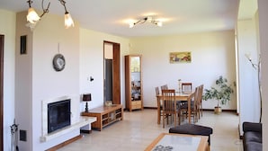 Una sala de estar con chimenea, una mesa de comedor con sillas, un sofá y una mesa baja.