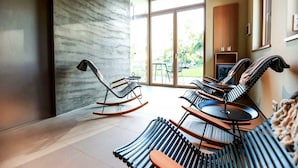 A modern living room with a large sliding glass door leading to an outdoor area. There are two rocking chairs and a sofa with a unique design. - Exklusives Landhaus auf Fehmarn (Fehmarn)