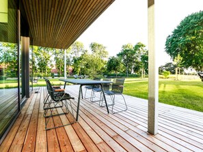 An outdoor patio with a wooden deck, metal-framed chairs, and a table. - Exklusives Landhaus auf Fehmarn (Fehmarn)