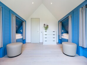 A modern bedroom with a high ceiling, a central door, and a white dresser. - Exklusives Landhaus auf Fehmarn (Fehmarn)