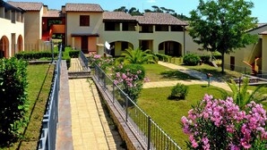 Un patio con un sendero que lleva a un edificio con varios balcones y un árbol.