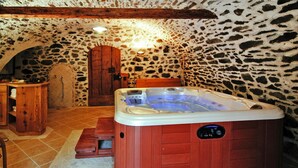 A rustic stone-walled room with a wooden bathtub, a wooden bench, and a wooden cabinet. - Apartment in Pellizzano With Paid Sauna (Pellizzano)