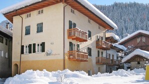 A multi-story building with balconies and a snow-covered roof, surrounded by snow. - Apartment in Pellizzano With Paid Sauna (Pellizzano)