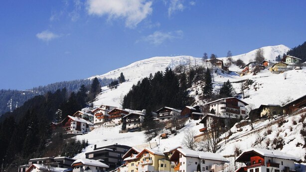 A snow-covered village with traditional chalet-style buildings, a prominent mountain in the background, and a clear blue sky. - Apartment Val Sinestra, Kappl (Kappl)