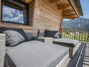 A wooden cabin with a balcony, wicker furniture, and a view of mountains. - Chalet Gamsknogel mit Privatem Pool und Whirlpool (Inzell)