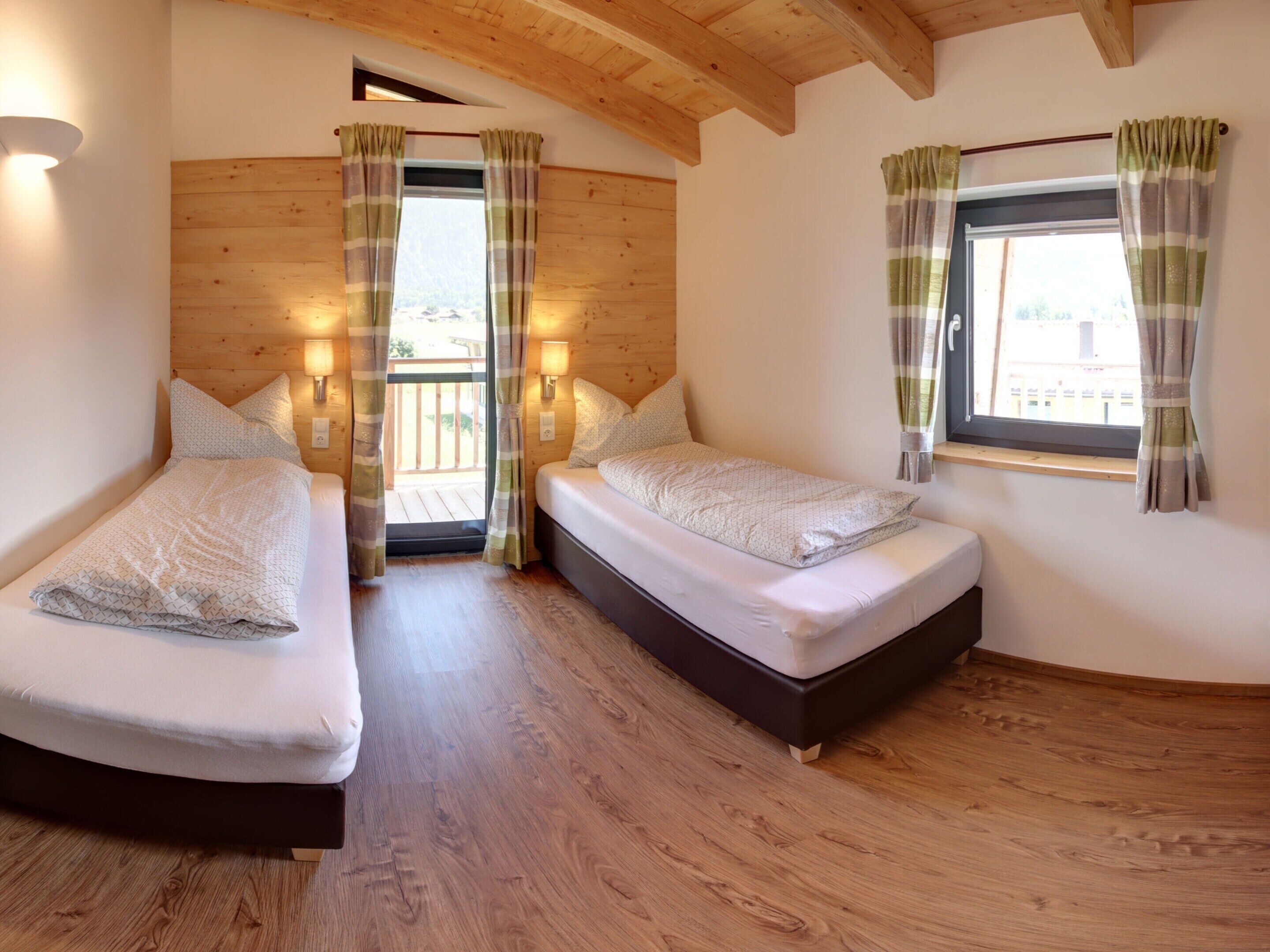 Una habitación pequeña y acogedora con dos camas, paredes de madera y un balcón.