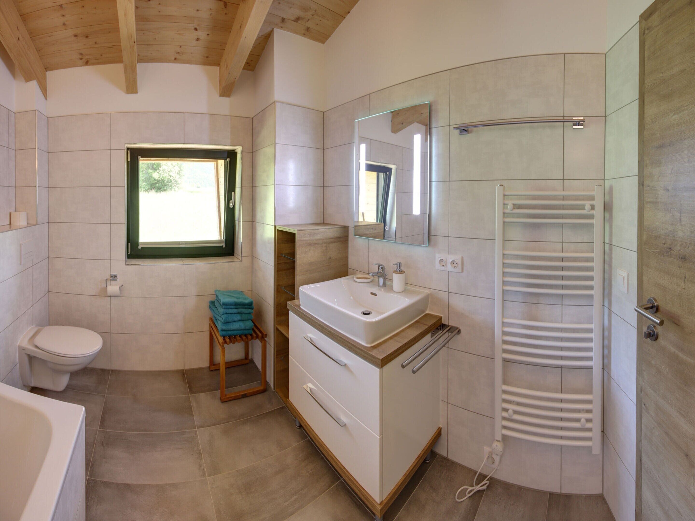 Et moderne badeværelse med toilet, håndvask og bruser.
