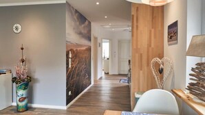 A modern interior with a wooden floor, a wall-mounted clock, a large abstract painting, and a heart-shaped decoration. - Das Ferienhus in Tonning (Toenning)