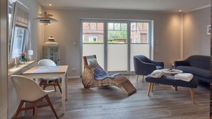 A modern living room with a dining area, a wicker chair, a sofa, and a table. - Das Ferienhus in Tonning (Toenning)