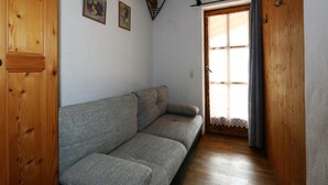 Un interior de madera con sofá, vigas de madera y una ventana con cortinas.