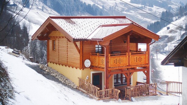 Una cabaña de madera con balcón, con vista a una montaña nevada.