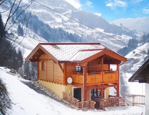 A wooden chalet with a balcony, set against a snowy mountain backdrop. - Holiday Home in Grossarl With Mountain Views (Grossarl)