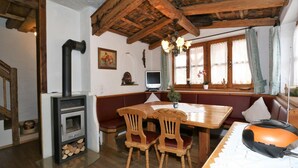 Un comedor rústico con una mesa de madera, dos sillas, un banco y una chimenea.