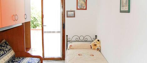 Un dormitorio con cama, sofá, armario y puerta que da a un espacio exterior.