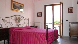 A bedroom with a bed, a nightstand, a dresser, and a window with a view. - Apartment in Cilento Near Sandy Beach (Ascea)