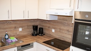 A modern kitchen with white cabinets, a wooden countertop, a built-in oven, and a coffee maker. - Lovely Apartment in Breitenbrunn With Shared Sauna (Breitenbrunn/Erzgeb.)