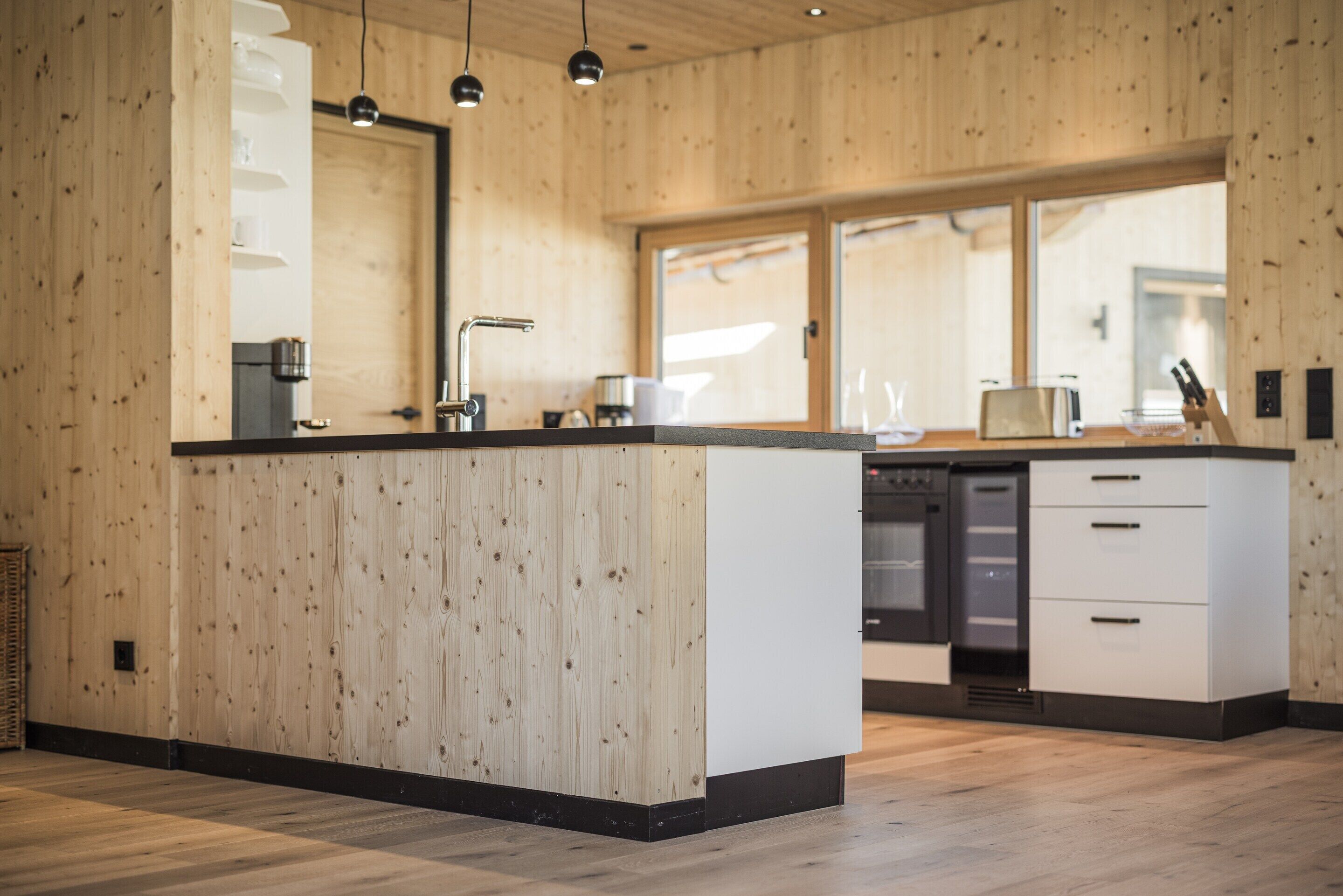 A modern kitchen with wooden walls, a central island, and built-in appliances.