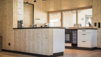 A modern kitchen with wooden walls, a central island, and built-in appliances.