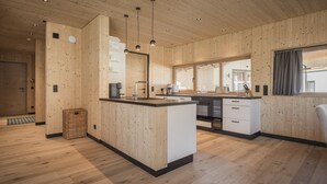 Una cocina moderna con paneles de madera, una isla central y un ventanal grande.