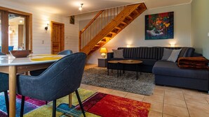 A modern living room with a dining area, a staircase, and a painting on the wall. - Doppelhaushalfte in Hasselfelde (Oberharz am Brocken)