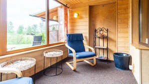 A cozy room with a wooden interior, a rocking chair, a small table, and a window with a view of greenery outside. - Doppelhaushalfte in Hasselfelde (Oberharz am Brocken)