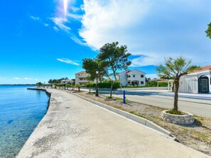 A coastal road with houses, clear skies, and a calm sea. - Apartment on Vir Island Near Sandy Beaches (Vir)
