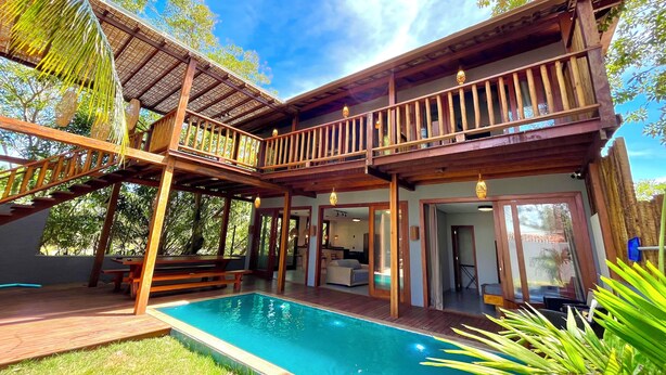 A two-story wooden house with a swimming pool, wooden deck, and a covered patio area.
