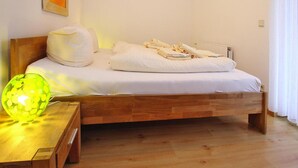 A neatly made bed with white linens, a wooden headboard, and a bedside table with a green glass lamp. - Appartement in Westerland auf Sylt (Sylt)