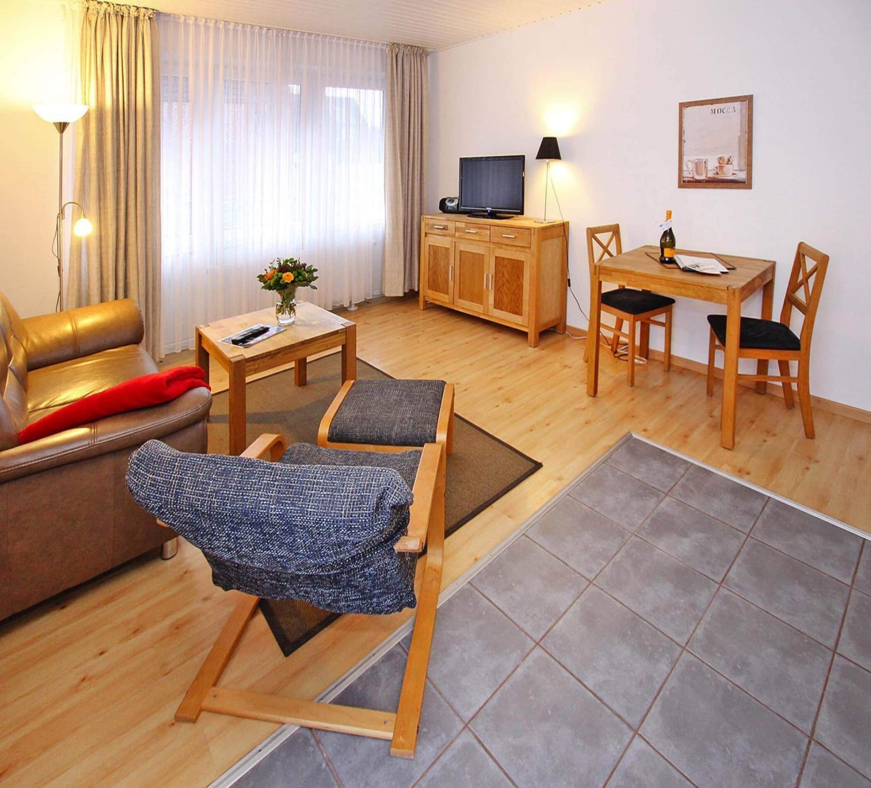 Un salon meublé comprenant un canapé, une table à manger en bois, un téléviseur et une lampe.