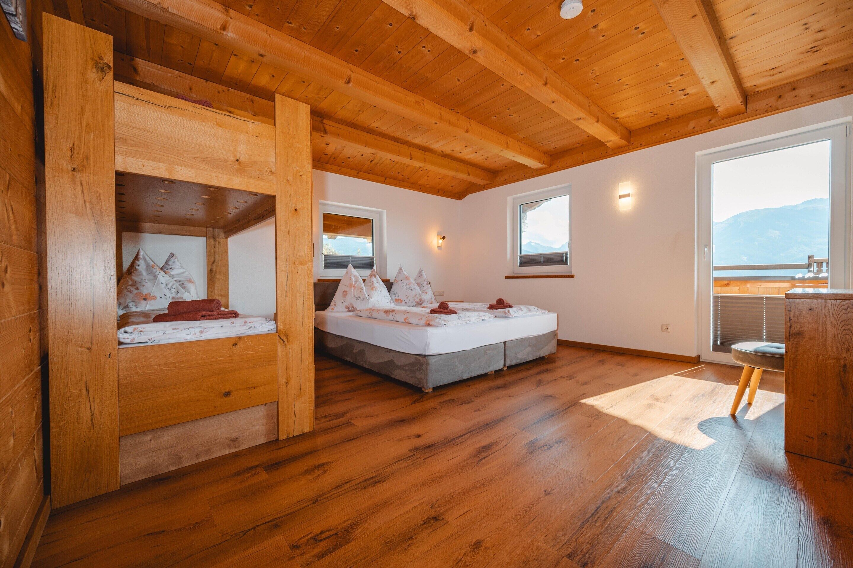 En stuga byggd av trä med en sovplats på ett loft, en våningssäng och en liten sittgrupp.