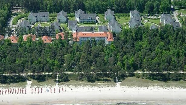 An aerial view of a coastal area with a beach and a cluster of buildings. - Ferienwohnung im Dunenpark Binz (Binz)