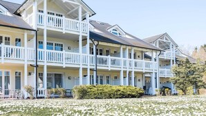 A multi-story hotel with balconies, a covered outdoor seating area, and a garden with white flowers. - Ferienwohnung im Dunenpark Binz (Binz)