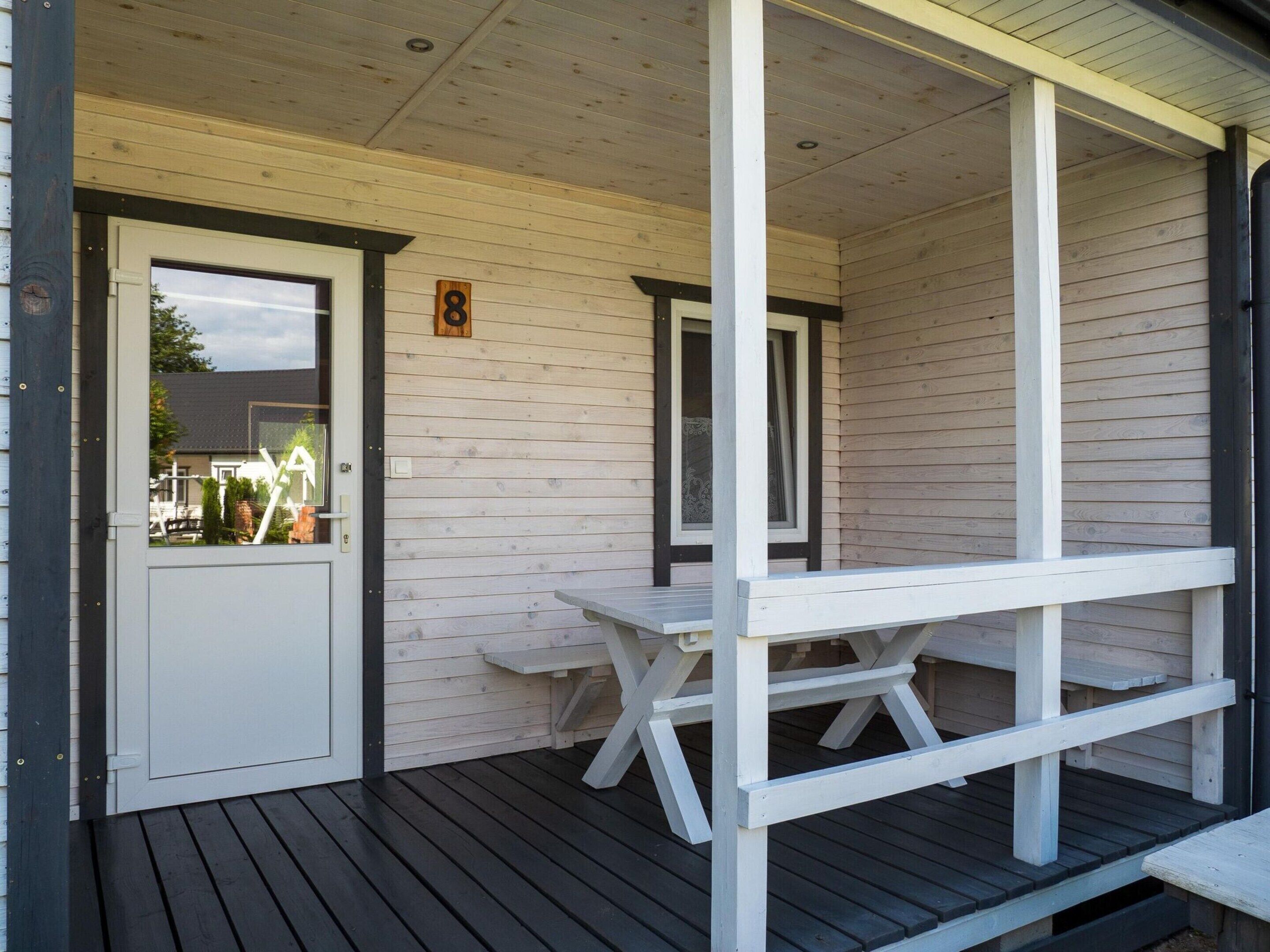 A wooden porch with a white door and a number 8 sign.
