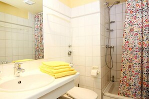 Et badeværelse med vask, spejl, toilet og bruser.